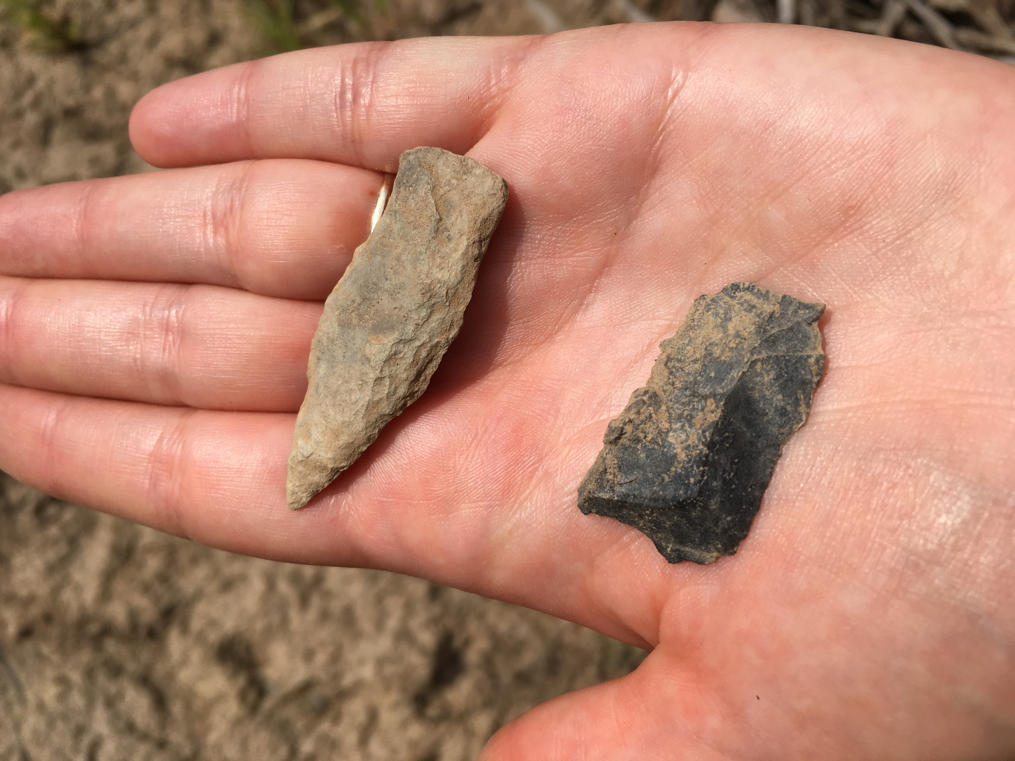 Two stone artifacts in a person's hand.
